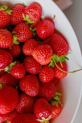 Fresh sweet strawberries in a white bowl on a white background. Seasonal berries.