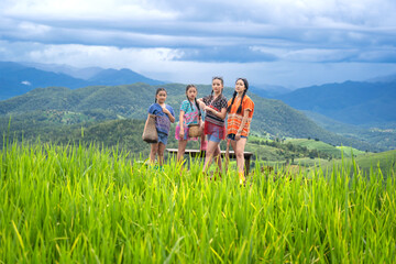 Group of pretty teenage travellers wearing custom-made Karen dresses in a natural green terraced rice fields at Pa Bong Piang rice fields, Mae Chaem, Doi Inthanon, Chiang Mai, Thailand.