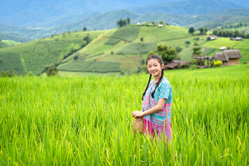 Pretty teenage travellers wearing custom-made Karen dresses in a natural green terraced rice fields at Pa Bong Piang rice fields, Mae Chaem, Doi Inthanon, Chiang Mai, Thailand.
