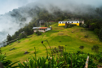 A misty landscape at El Pital, El Salvador’s highest point, showing rustic buildings and lush...