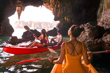 Tourists on a kayaks sail through a cave of a limestone island in a tropical sea in Thailand, Krabi...