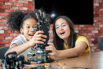 Children Learning Robotics, Young Girls Engaged in Robotics and STEM Learning, Diverse Kids Building a Robot Arm in a Science Workshop, Two Girls Exploring Technology and Innovation