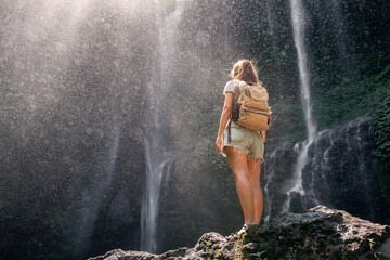 Back view of a young woman with Sekumpul waterfall in the background, Bali Island, Indonesia