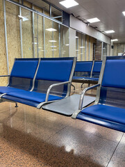 The image showcases modern blue airport seating with metal frames, positioned in a spacious...
