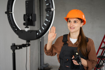 Female blogger builder recording video with ring light at construction site. Renovation and content...