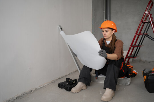 Female Renovator Studying Apartment Blueprint Plan indoors