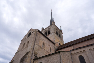 Fototapeta premium Looking up abbey church at Swiss city of Payerne on cloudy spring day. Photo taken June 6th, 2025, Payerne, Switzerland.