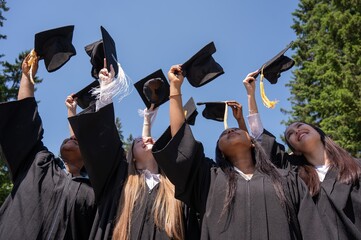 Young girls of different nationalities pull their graduation caps up. 