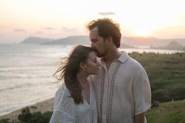 Young woman and man kissing against sunset in nature. Honeymoon, couple in love after wedding....