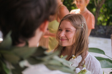 Outdoor wedding ceremony with ocean and green hills in the background. Bride in white dress and...