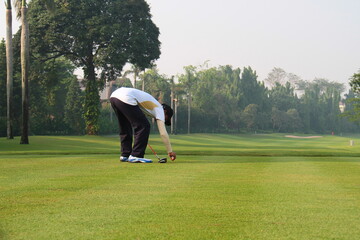 Unidentified male amateur golfer placing a golf ball on tee. 