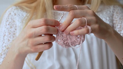 Women's hands crocheting an openwork product. Timeless craft of crochet. 