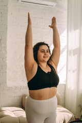 A young curly-haired plus-size woman doing breathing exercises.Healthy lifestyle.