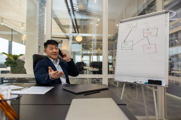 Asian young manager having a phone call and looking busy and involved