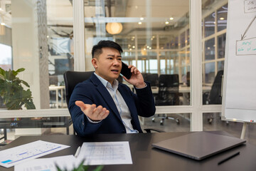 Asian young manager having a phone call and looking busy and involved