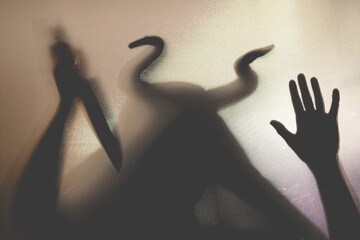 Horror, halloween background - Shadowy figure with horns behind the glass