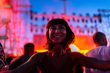 Young woman dancing at concert, having fun at night on open air stage. Sexy woman enjoying music at...