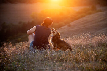 Young woman with her dog watching the sunset