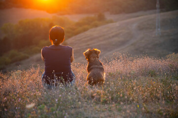 Young woman with her dog watching the sunset
