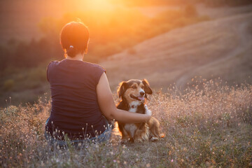Young woman with her dog watching the sunset
