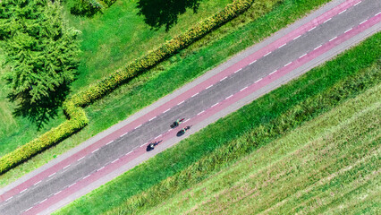 Group of people cycling on bicycle lane aerial drone view from above, beautiful cycling path,...