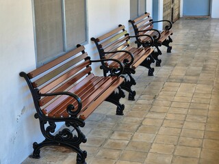 A row of vintage decorative wooden chairs along the tiled corridor wall in a public building.