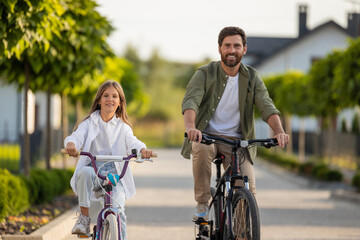 Obraz premium Family bike ride with father and daughter on park path near home