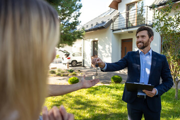 Real state agent giving the key from a new house to the clients