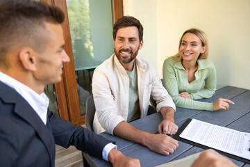 Real estate agent discussing deal with couple on laptop outside home