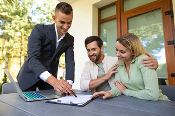 Agent presenting house details to clients with laptop in