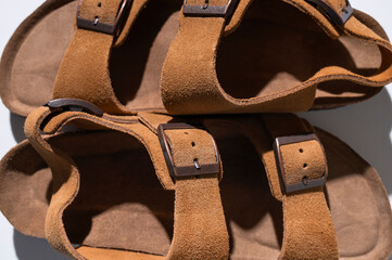 Brown sandals made of genuine leather on a cork sole on light gray background flat lay top view....
