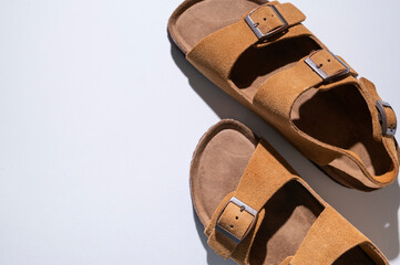 Brown sandals made of genuine leather on a cork sole on light gray background flat lay top view....