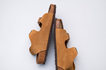 Brown sandals made of genuine leather on a cork sole on light gray background flat lay top view....