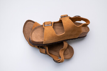 Brown sandals made of genuine leather on a cork sole on light gray background flat lay top view....