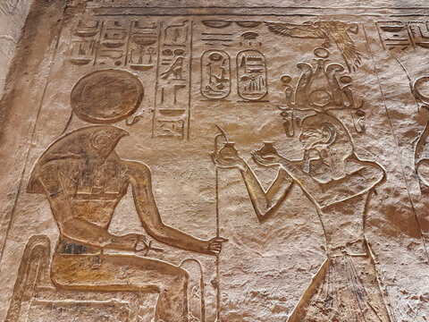 Horus receiving offerings from pharaoh in egyptian bas relief carving