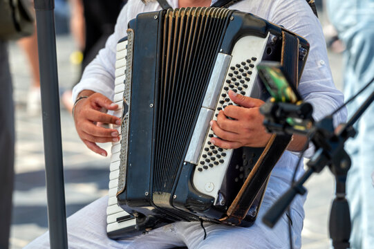 Musician playing accordion in a lively street in Crete, Greece during sunny afternoon