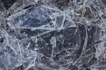 Cracked ice on a puddle texture background cracks and shards on a dark background