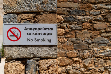 No smoking sign on a stone wall in a historic location during a sunny day