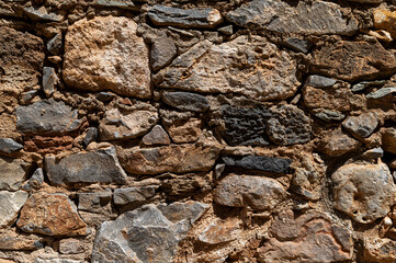 Detailed textures of an ancient stone wall in a deserted location during bright daylight