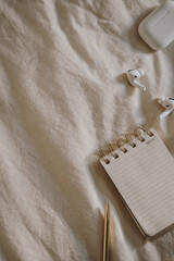 Flat Lay of Notepad and Earbuds on Fabric