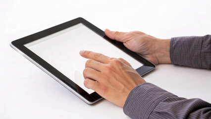 A person using a tablet with a blank screen on a white surface.