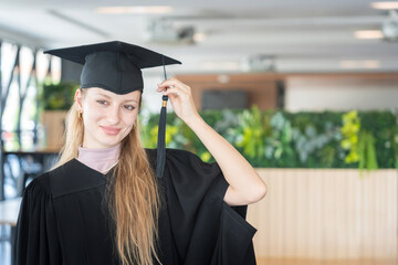 Portrait of a Young Woman on Her Graduation Day, Smiling Female Graduate in Cap and Gown, Proud...