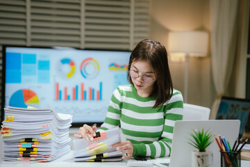 A stressed woman works late at a cluttered desk, surrounded by papers and charts, overwhelmed with...