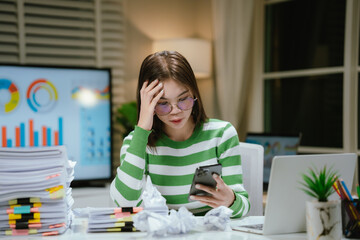 A stressed woman works late at a cluttered desk, surrounded by papers and charts, overwhelmed with...