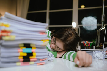 A stressed woman works late at a cluttered desk, surrounded by papers and charts, overwhelmed with...
