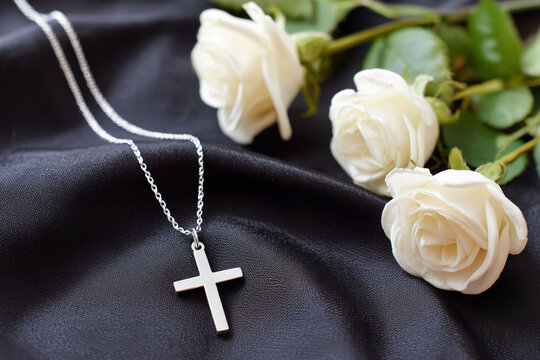 Elegant cross necklace with white roses, funeral flower bouquet on black silk fabric background