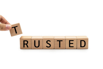 Hand putting wood cube block with TRUSTED text isolated on white background. Brand building for...