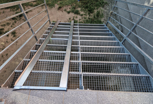 ramp combined with a gray concrete staircase and a handrail specially adapted for wheelchairs. security tasteful solution for entering a city park. sheet metal rails, pram, mother, wheel, pushing out  - Powered by Adobe