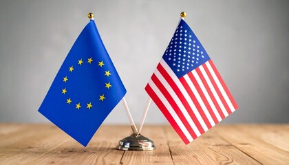 EU and US miniature flags side by side on wooden surface with gray background