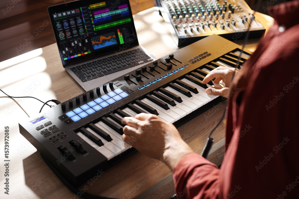 Poster man working with midi keyboard at wooden table indoors, above view